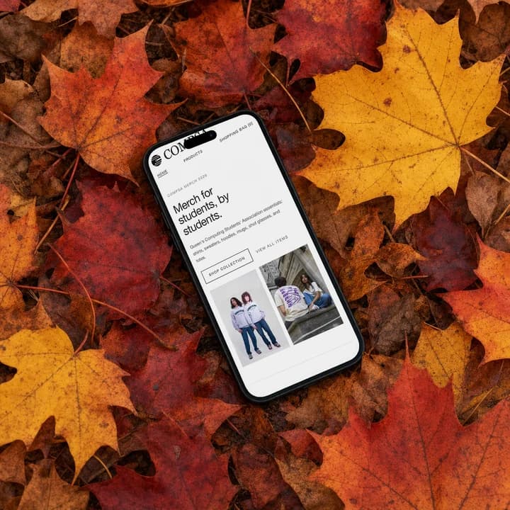 The merch store home page on an iPhone lying in fallen maple leaves